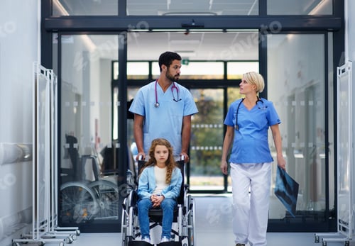 Preview: Pregnant doctor with her colleague pushing litle girl at wheelchair at pediatric department.