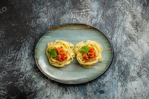 Preview: Above view of delicious pasta meal with tomato meat and green on a blue plate on ice background