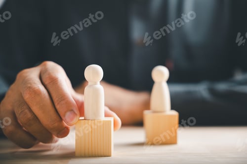 Preview: Hand places wooden figure on a block, symbolizing leadership, success, or team building.