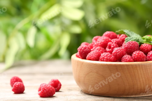 Preview: Bowl with ripe aromatic raspberries on table against blurred background