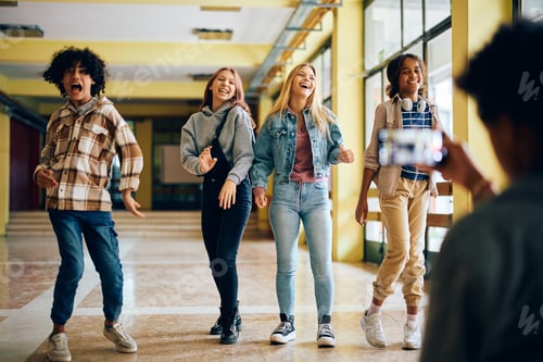 Preview: Cheerful high school students goofing around while a friend is filming them with a phone.