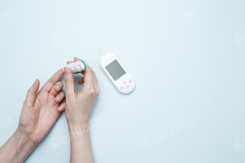 Preview: Female hands holding glucometer for measuring blood glucose levels, lancet