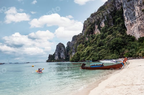 Preview: Tourist canoeing with wooden boat and mountain on coastline in tropical sea at Phi Phi Island