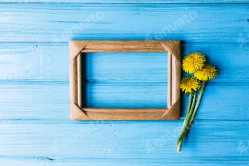 Preview: Dandelion with a wooden photo frame on a blue background