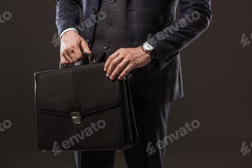 Preview: cropped shot of businessman holding briefcase isolated on black
