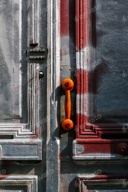 Preview: brown vintage telephone receiver on handle door. Closed wooden door building entrance on street with