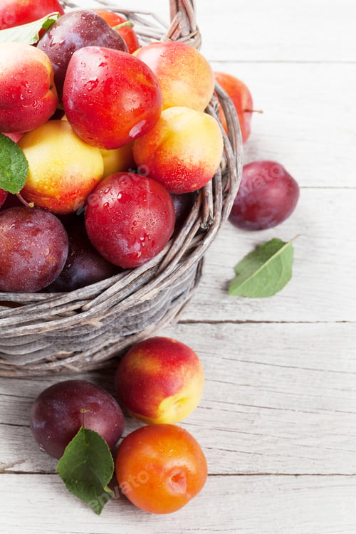 Preview: Fresh ripe peaches and plums in basket