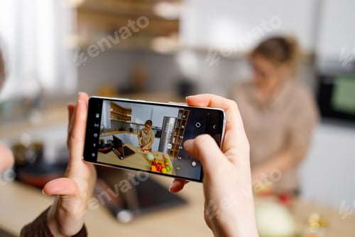 Preview: Girl with smartphone recording video of her mother cooking