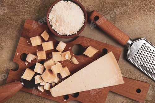 Preview: Freshly sliced and grated cheese, parmesan cheese, on a wooden chopping board, rustic style,