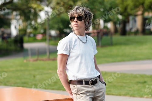 Preview: Tough androgynous person posing in a park.
