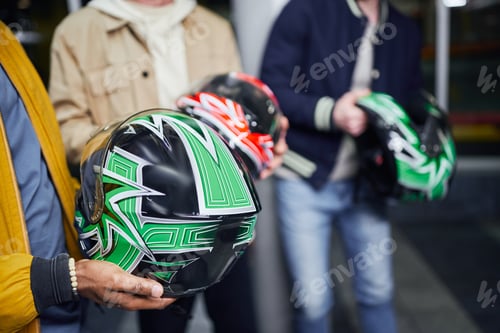 Preview: cropped african american man holding helmet near friends inside of indoor racing track, karting