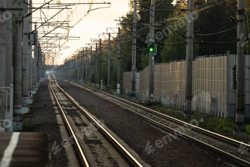 Preview: Empty railway tracks at sunset, forest on background. Perspective of electrified high-speed railroad