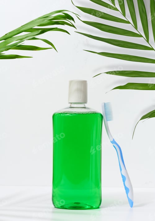 Preview: Refreshing mouthwash in a transparent plastic bottle and a toothbrush on a white background