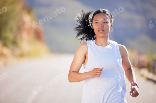 Preview: Active mixed race young woman running for exercise outdoors. Athlete jogging for a refreshing cardi