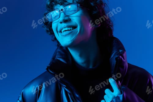 Preview: Man in winter jacket model poses in glasses smile, hipster lifestyle, portrait blue background