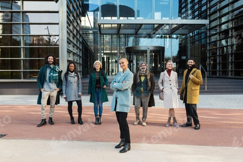 Preview: Professional business woman standing out from a group of business people while standing outside the
