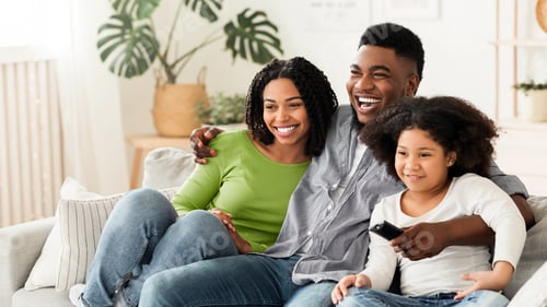 Preview: Black family of three relaxing on couch, watching tv together