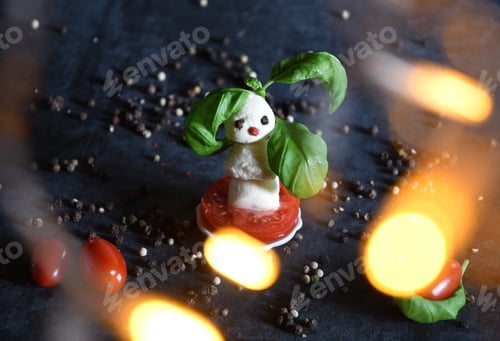 Preview: snowman canapes of mini balls of mozzarella cheese, decorated with basil and cherry tomatoes, bokeh