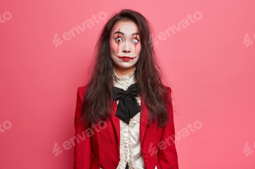 Preview: Shocked brunette woman with scars on face prepares for halloween festival stares bugged eyes tries t