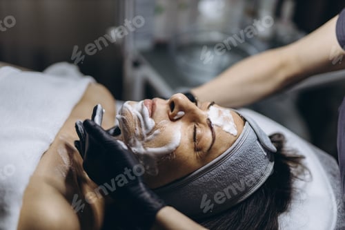 Preview: Middle aged woman receiving facial cleansing and care at a cosmetologist office