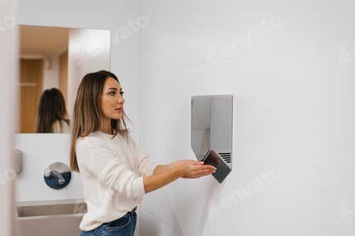 Preview: Caucasian Woman Dries her Hands with hot Water using a Dryer