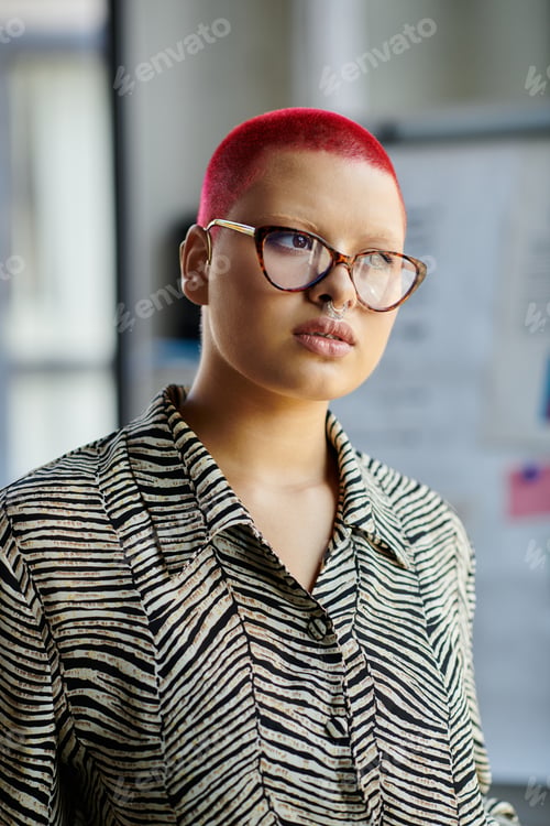 Preview: Striking bald woman with red hair and glasses in a stylish striped shirt expresses confidence