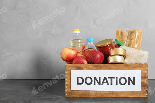 Preview: Donation box with food on table against light background. Space for text