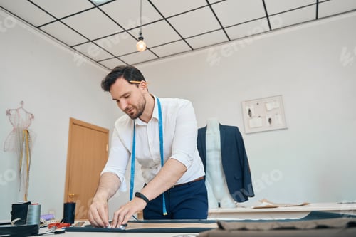 Preview: Couturier in sewing workshop chalks pattern on a black fabric