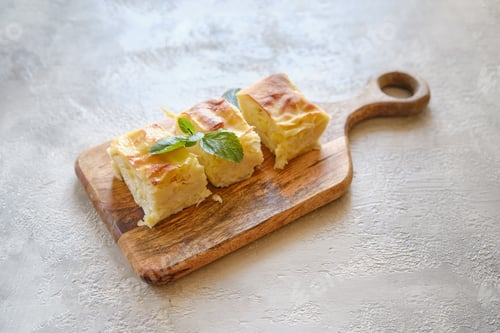 Preview: Three pieces of Georgian cheese pie Achma on wooden cutting board