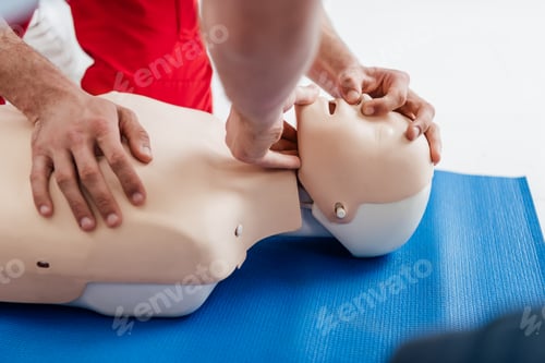 Vista previa: vista recortada de hombres practicando la técnica de reanimación cardiopulmonar con un maniquí durante el entrenamiento de primeros auxilios