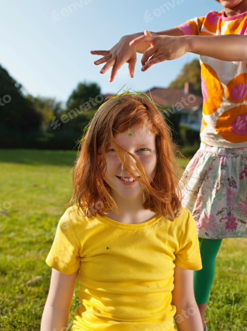 Preview: Girl putting grass on friends head, portrait