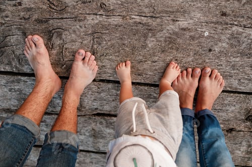 Preview: Bare feet of family. Wooden bridge. Mom, dad and baby walk bare feet on the wooden bridge. Happy