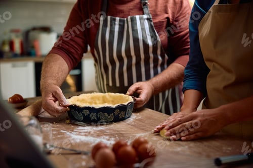 Preview: Close up of couple preparing homemade pie for the holidays.