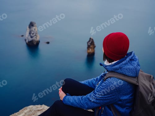 Preview: Back view of woman on shore of North sea on cold winter day.