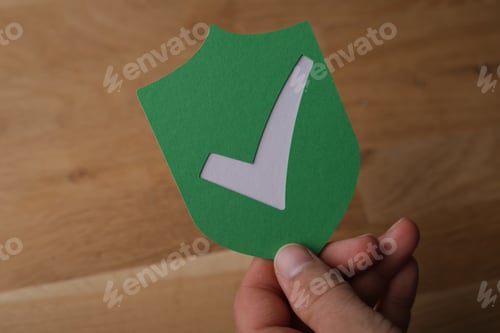 Preview: Closeup shot of a man holding a green protection shield icon with a white checkmark on it