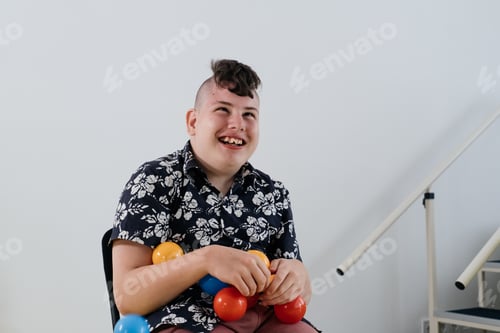 Preview: Happy teenage cerebral palsy child over white wall in rehabilitation center