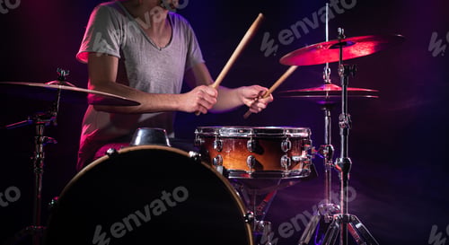 Preview: The drummer plays the drums. Beautiful blue and red background, with rays of light.