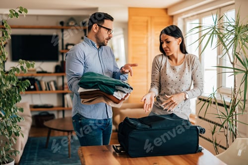 Preview: Couple arguing while preparing for travel, packing suitcase, portrait.