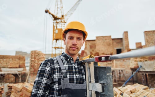 Preview: Ladder in hands. Construction worker in uniform and safety equipment have job on building