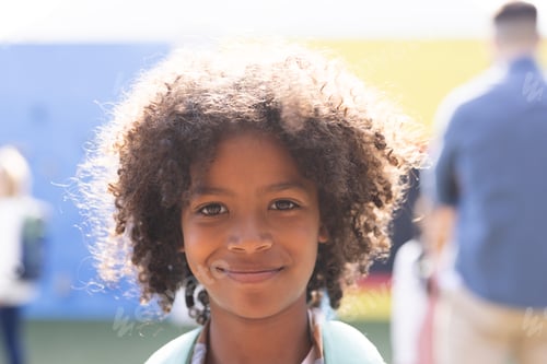 Preview: Portrait of smiling african american elementary schoolboy in school playground, copy space
