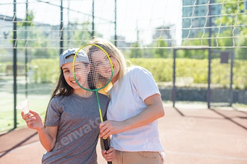 Preview: Mother and daughter are playing badminton outside in the yard on summer hot day
