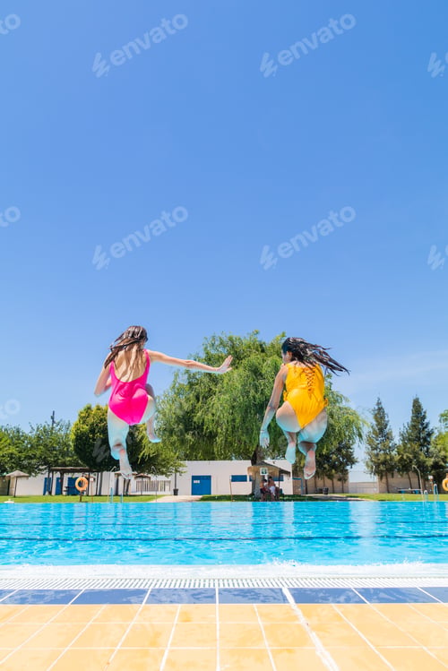 Preview: Two young girls jumping into the pool. Summer begins concept. Copy space