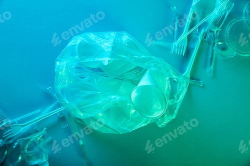 Preview: top view of crumpled plastic bag, cups and forks in blue light