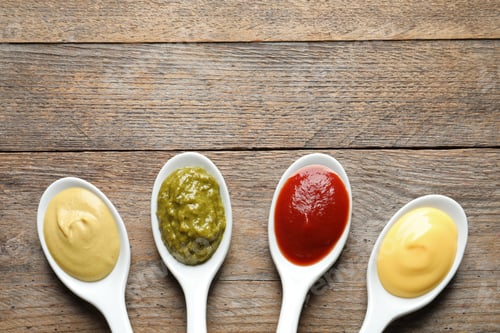Preview: Spoons with different sauces and space for text on wooden background, flat lay