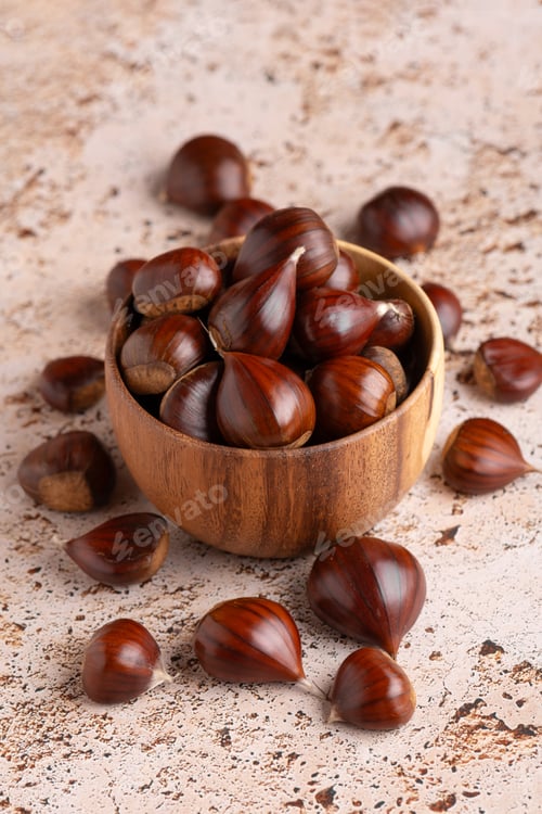 Preview: Autumn chestnuts in rustic wooden bowl on beige stone kitchen table