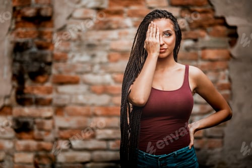 Preview: Woman With Long Afro Braided Hair Posing Outdoor Against A Brick Wall