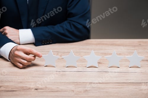 Preview: cropped view of man in formal wear pointing with finger at star isolated on grey, quality concept
