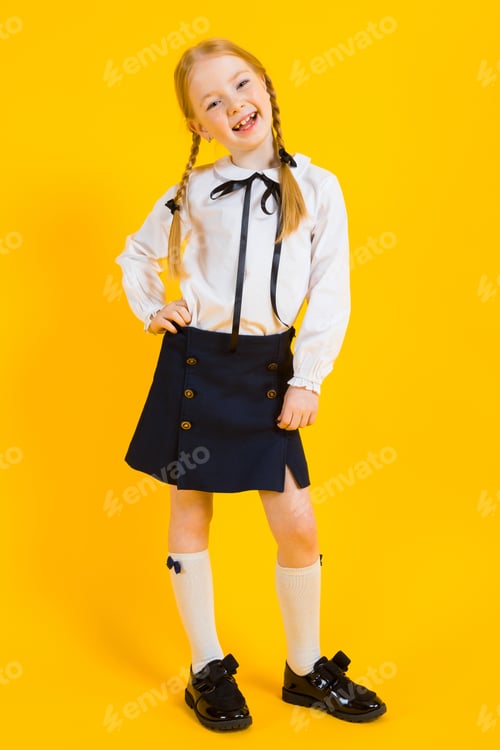 Preview: Girl with red pigtails on a yellow background. A beautiful girl is standing with her leg bent at the