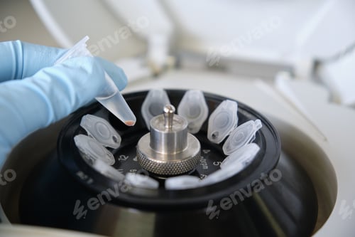 Preview: Close up of a researcher hand holding an eppendorf tube with a pellet over a centrifuge in a lab