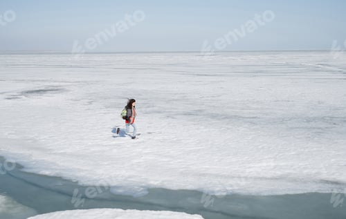 Preview: Young adult woman outdoors travelling with backpack in icy landscape